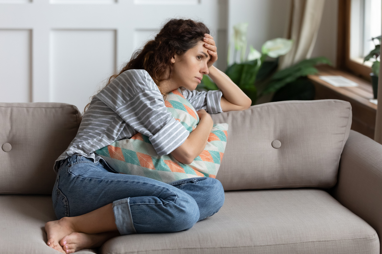 Woman on a couch feeling stressed out. 