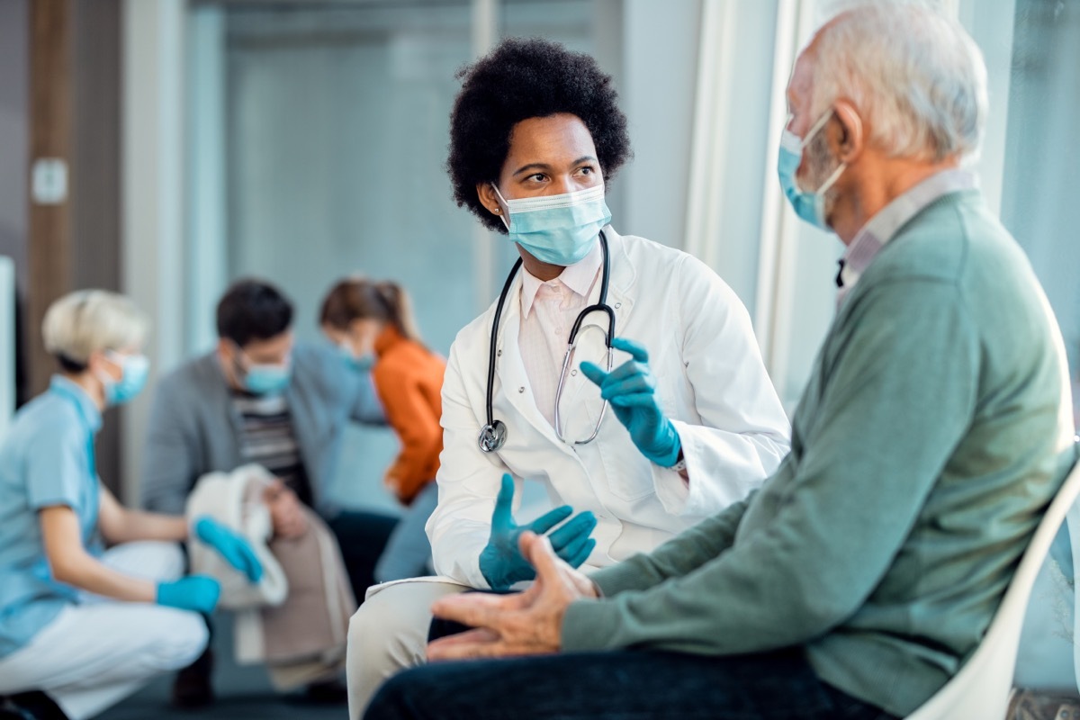 young doctor treating senior male wearing a surgical mask