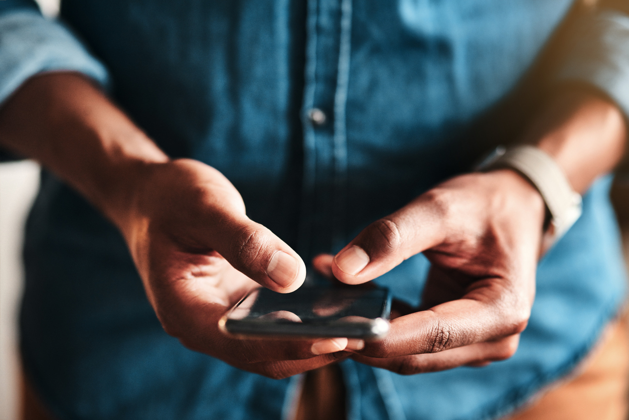 A close-up of a person's hands holding an iPhone and texting