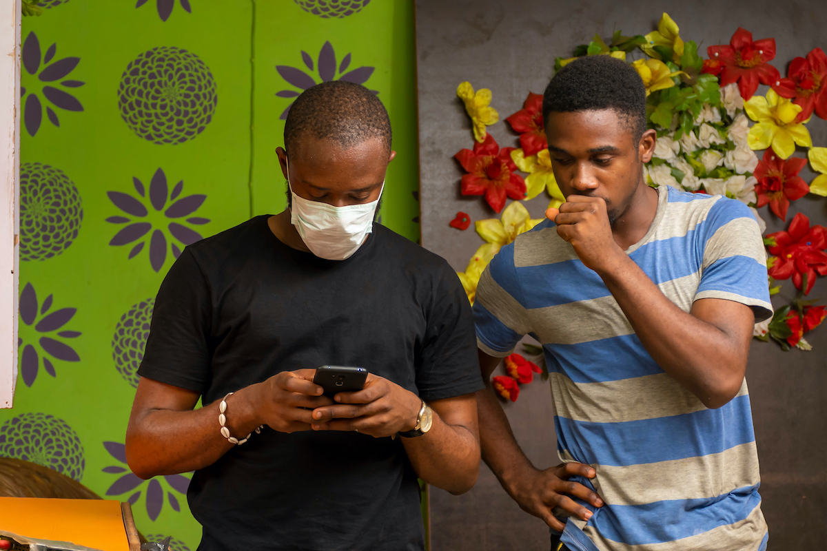 photo of two black men, one who's coughing and one who's not