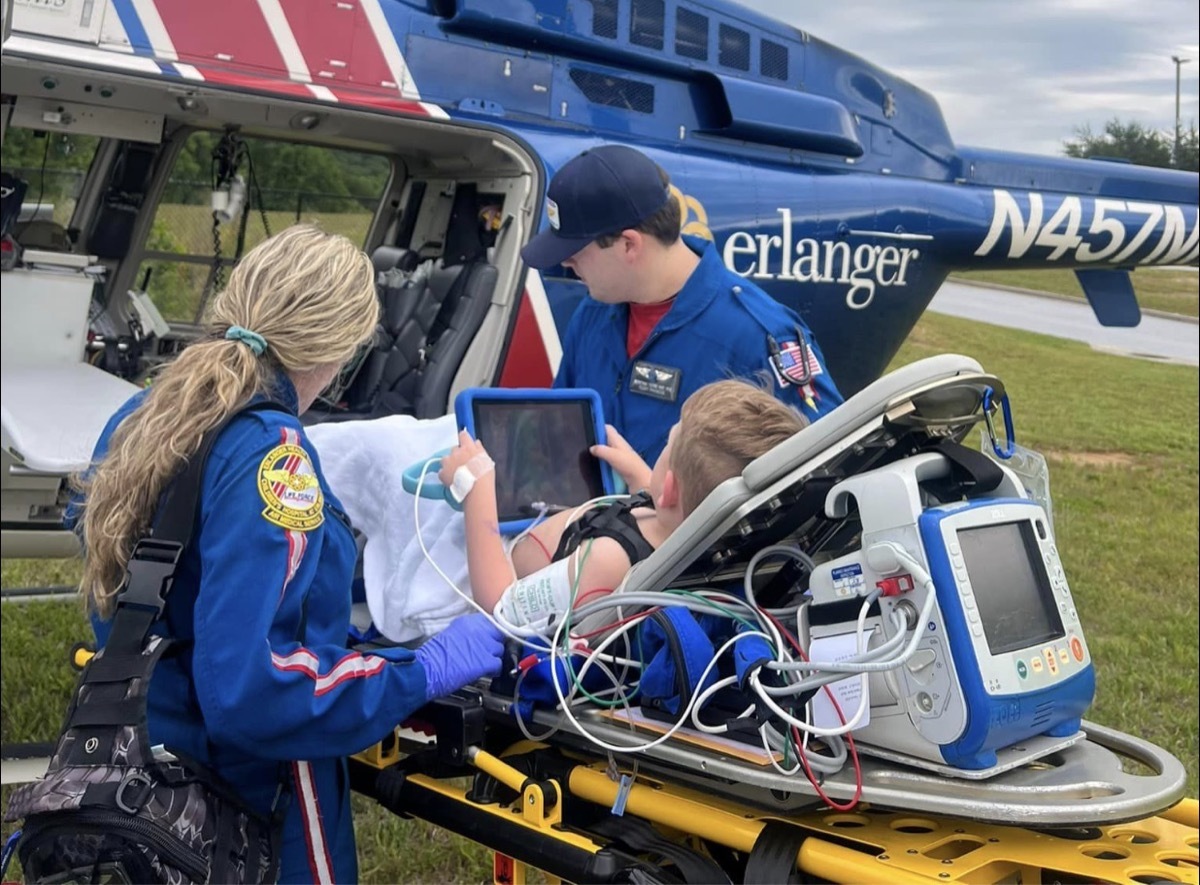 A young boy on a stretcher being placed onto a medical helicopter by two EMS workers