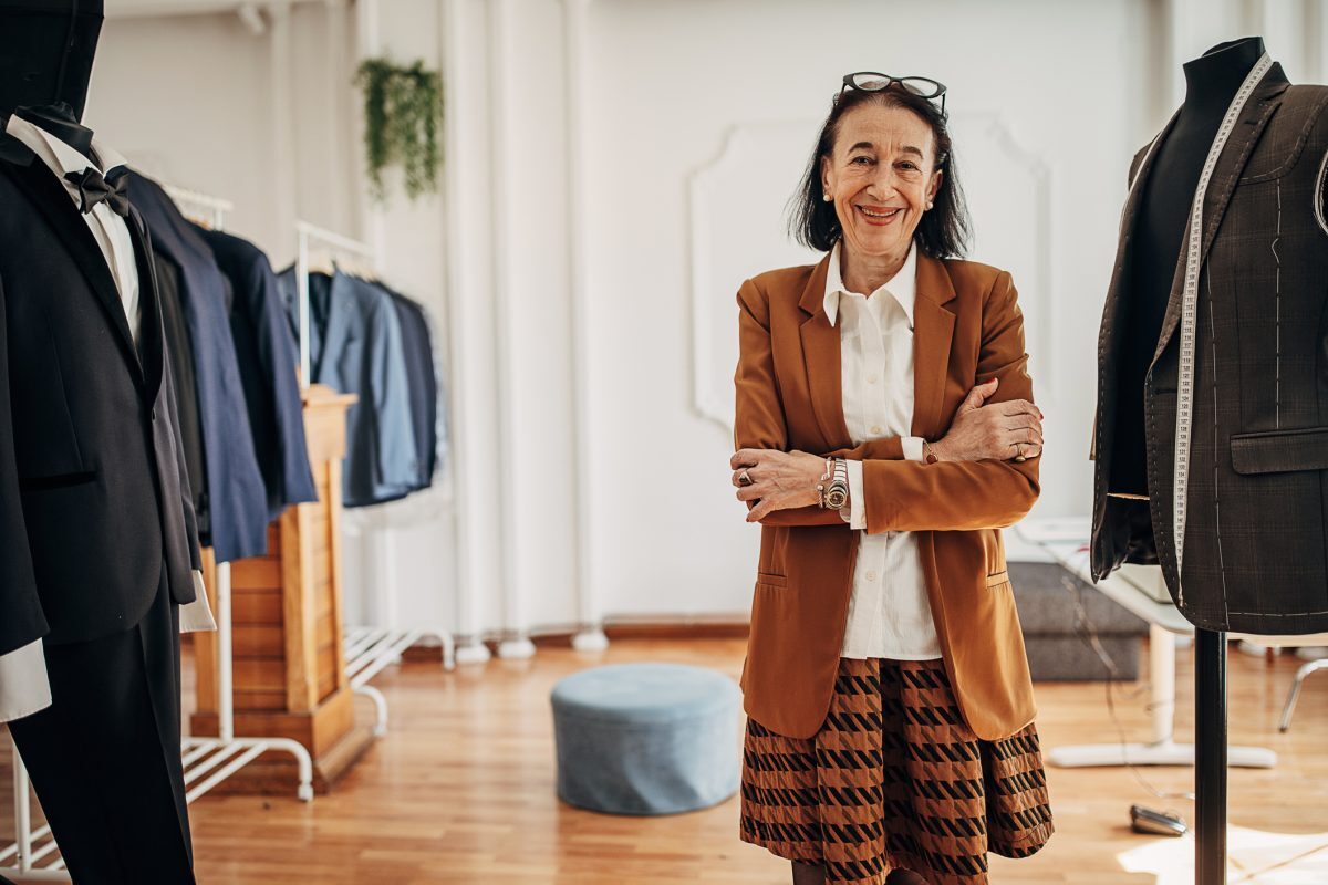 Older woman wears brown blazer in fashion atelier