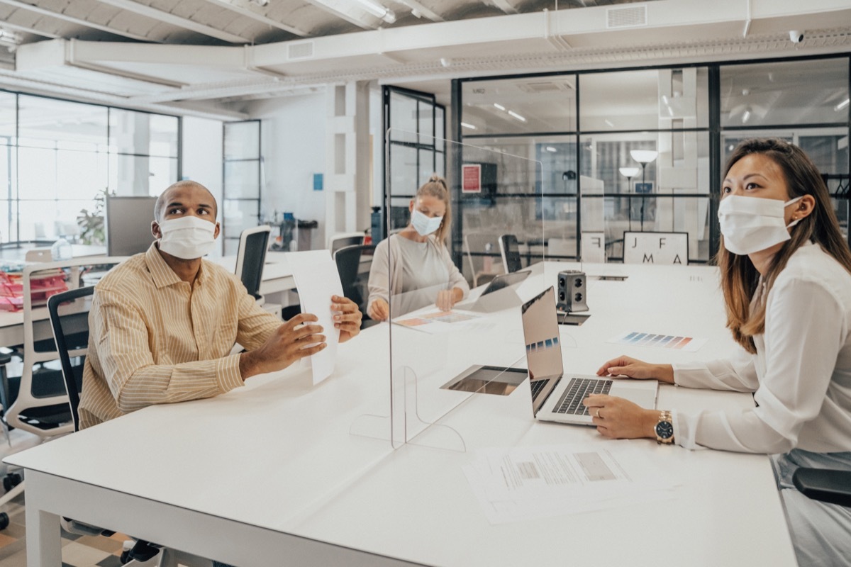 Businesspeople working at office with glass partition dividing them