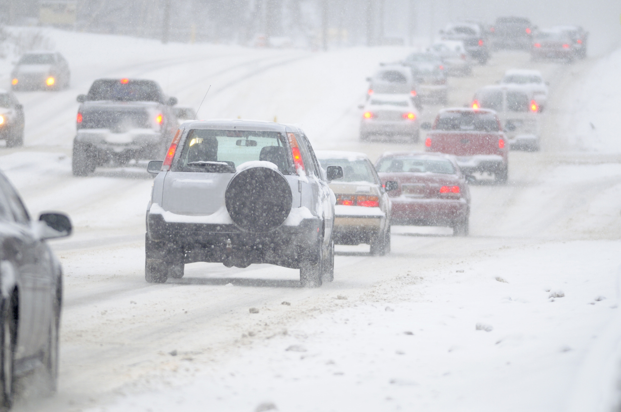 Cars driving on a highway during a snowstorm