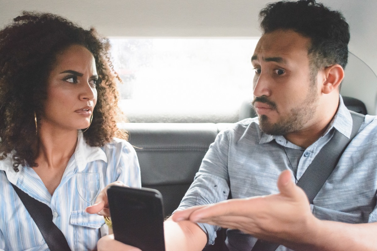 young couple with relationship problems arguing in the backseat of a car