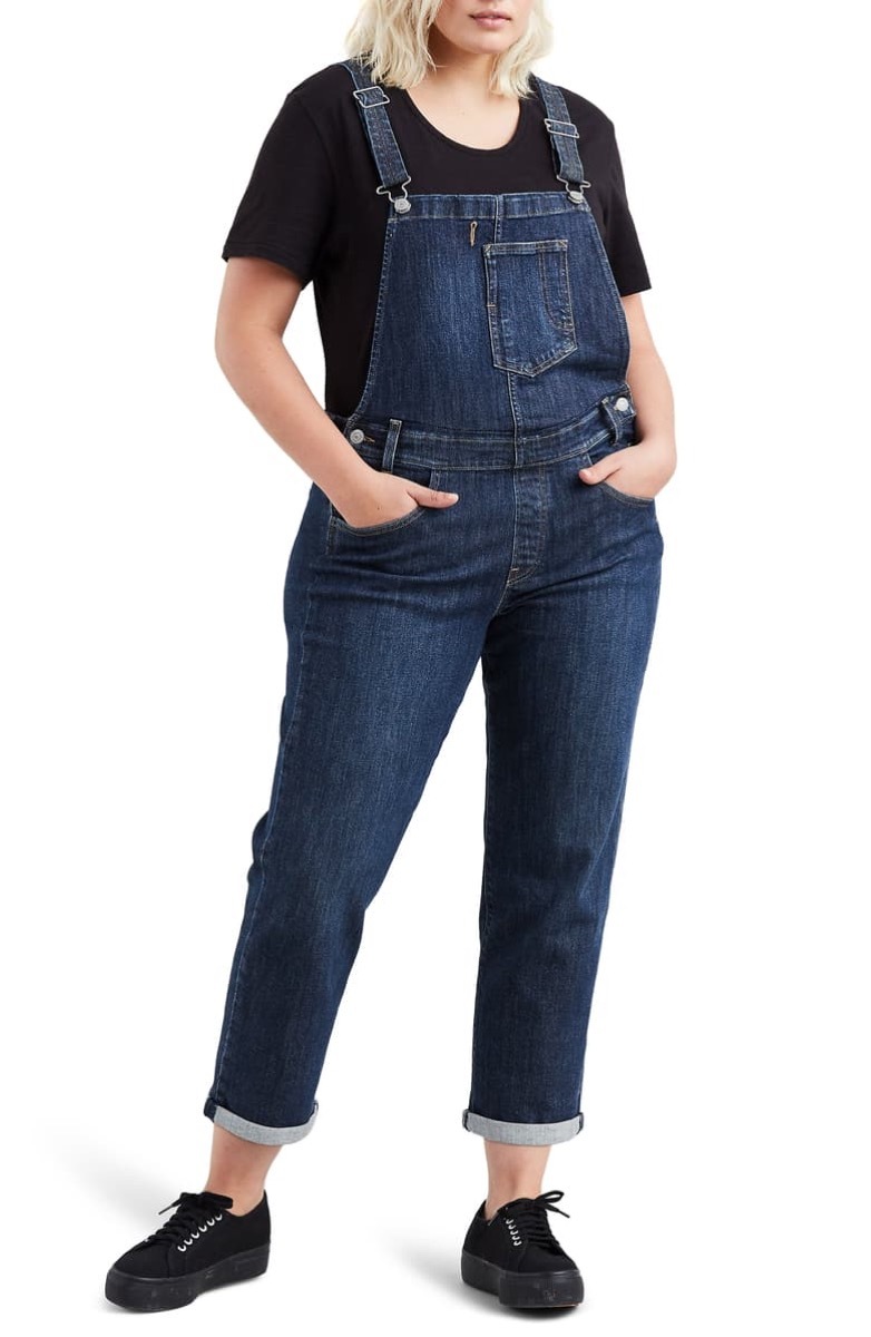 Woman wearing dark wash overalls