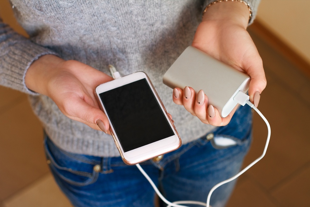 Woman Holding a Phone Attached to a Portable Charger