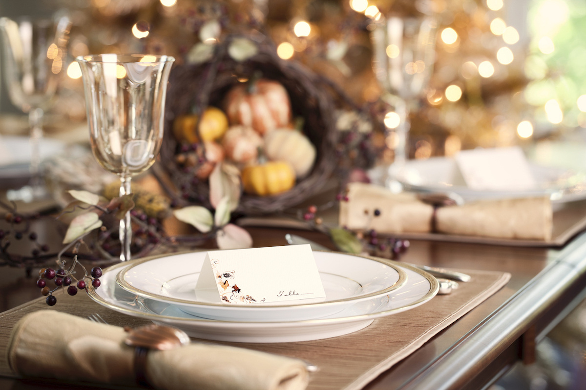 Autumn holiday Thanksgiving dining with place cards and traditional centerpiece filled with pumpkins and gourds.