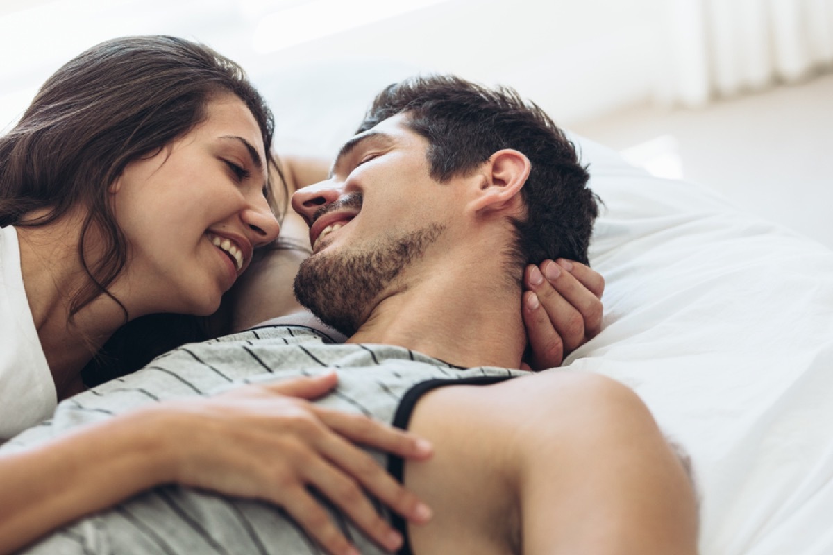 young couple smiling at each other under the sheets