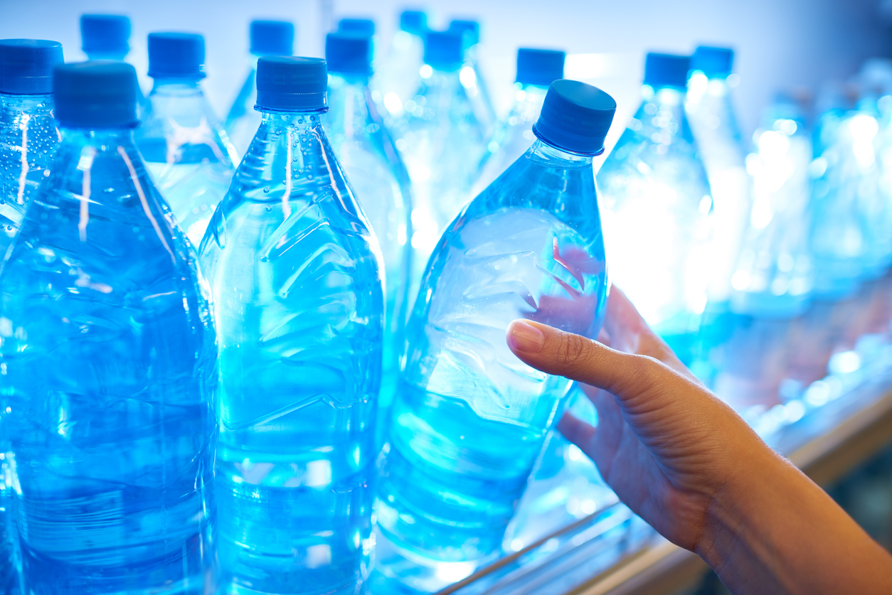 A hand taking bottled water off of a shelf