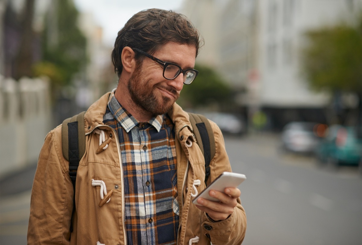 man looking at phone confused in city