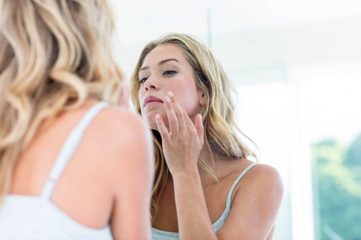 Woman looking at her skin in the mirror