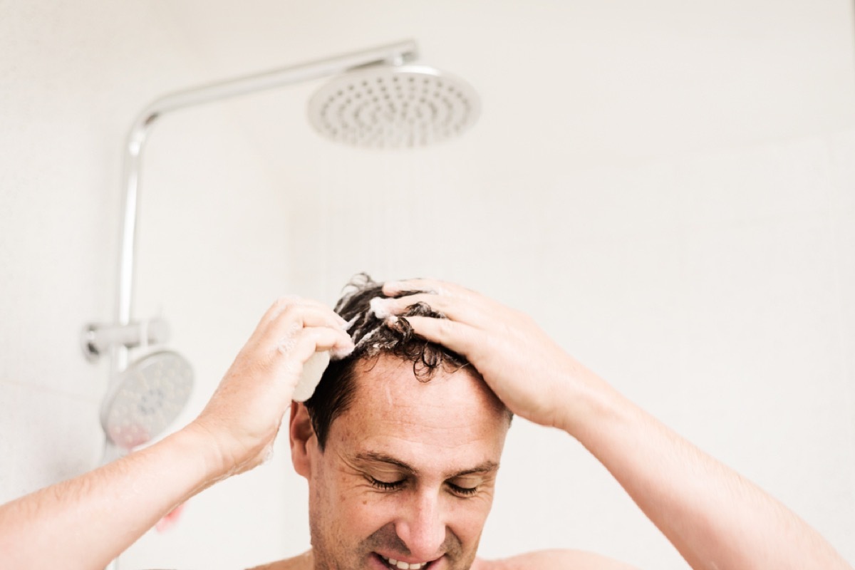 middle aged man soaps up hair in shower