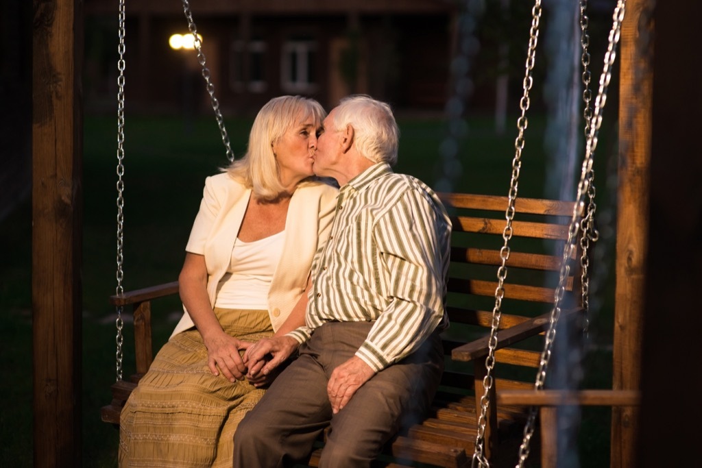 old couple kissing on a porch swing