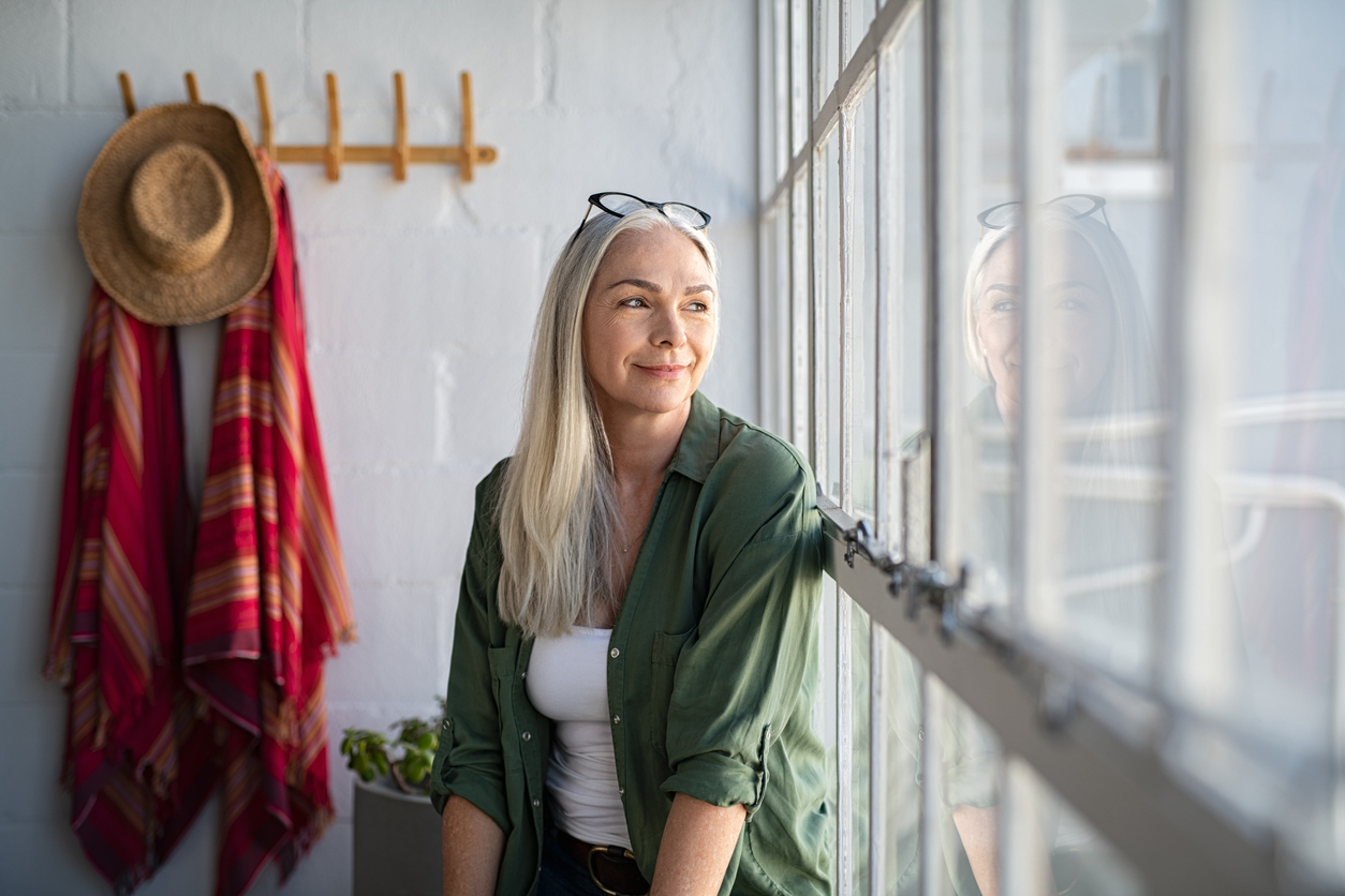 Woman sitting by window, looking outside.