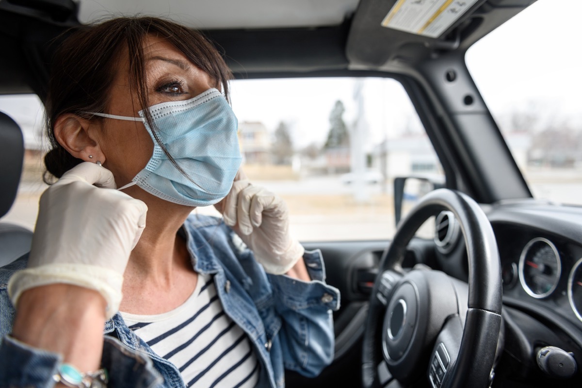 Mature woman removing her protective mask once in the car