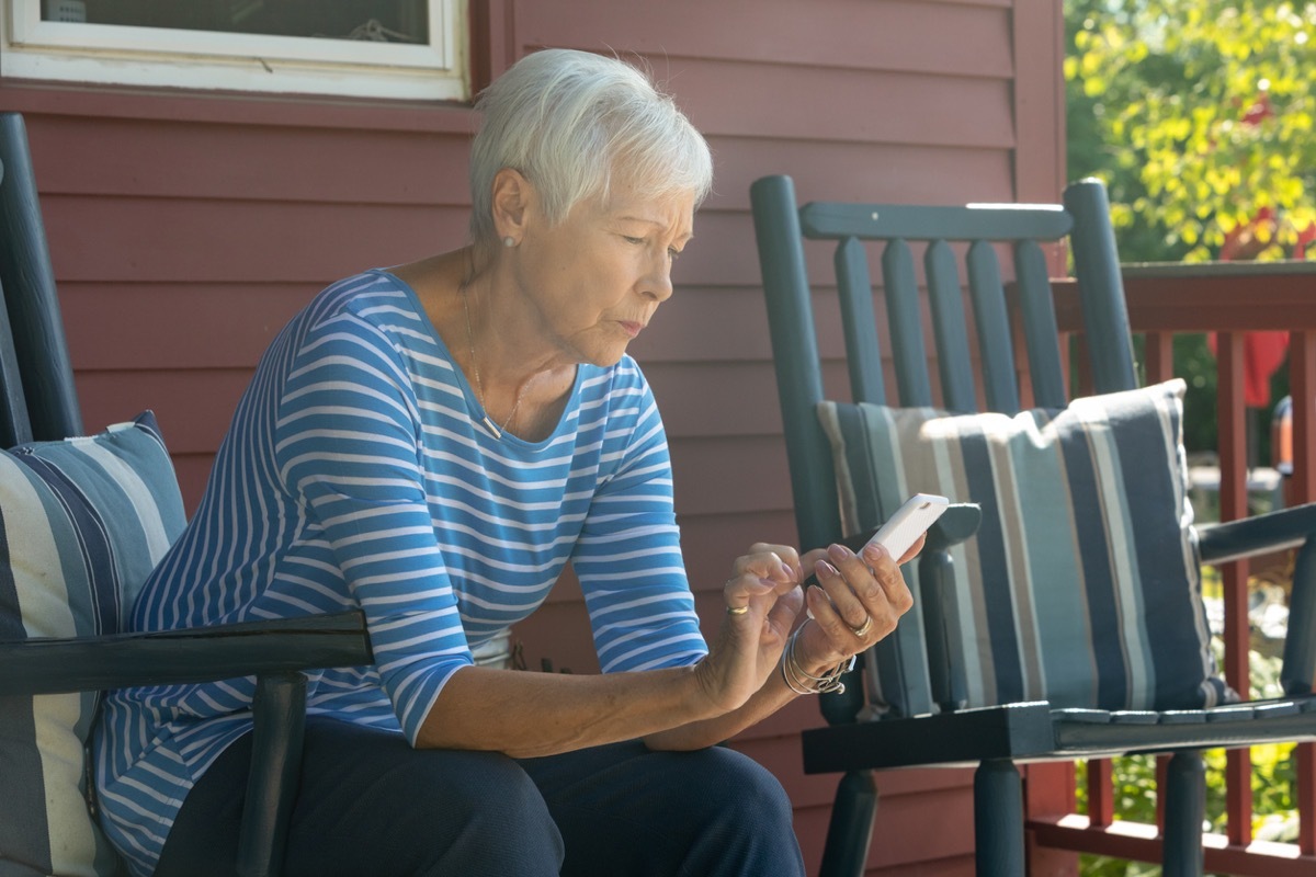 older white woman texting outside while looking concerned