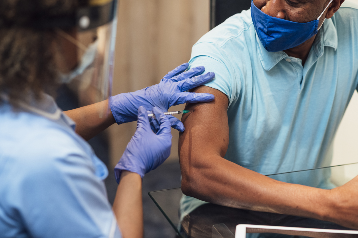 A female healthcare worker injects a middle-aged man with the COVID-19 vaccine.