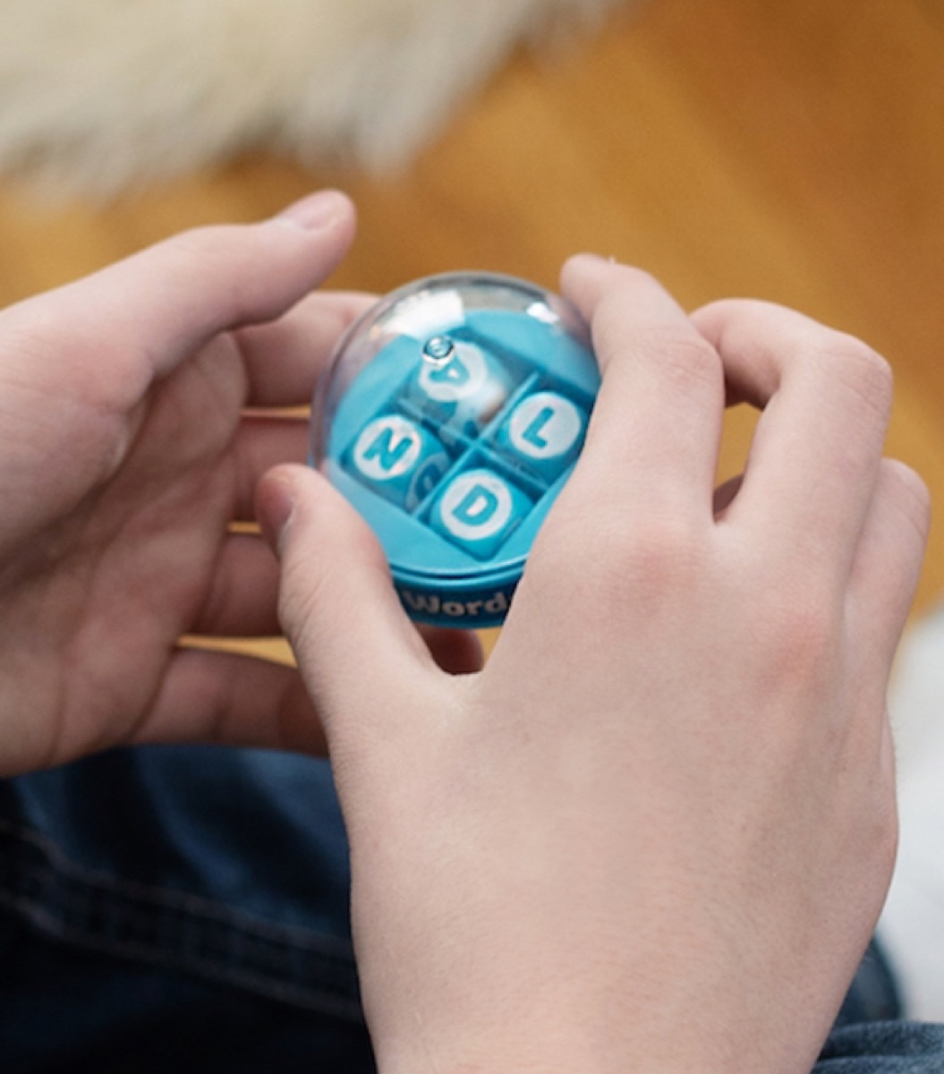 white hands holding blue letter toy