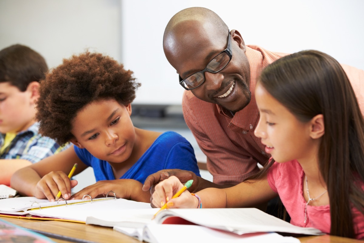 Male teacher helping multicultural students