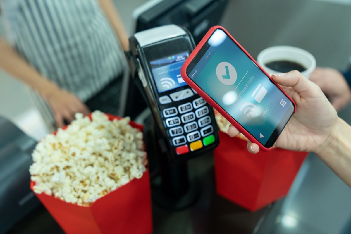 Close-up on a customer making a contactless payment at the concession stand at the cinema using a cell phone