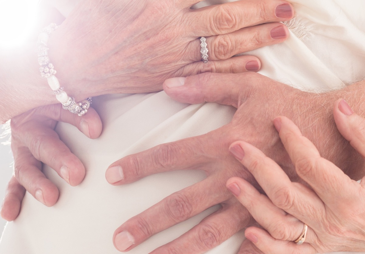 Older couple cuddling together when man embracing his wife's waist