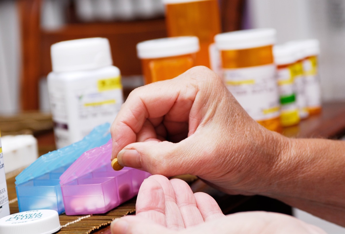 Senior woman taking meds from pill organizer