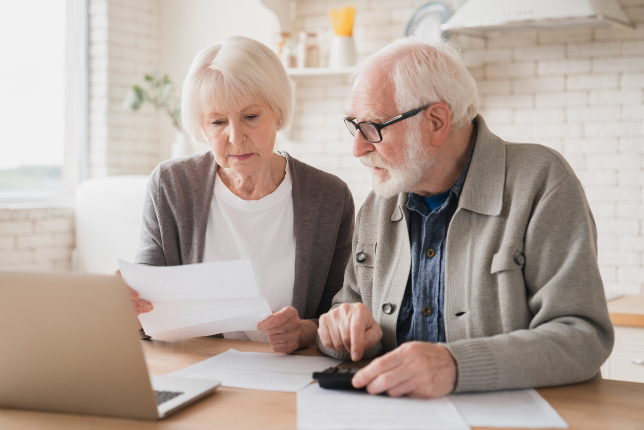 A senior couple sitting together with a laptop and calculator paying bills