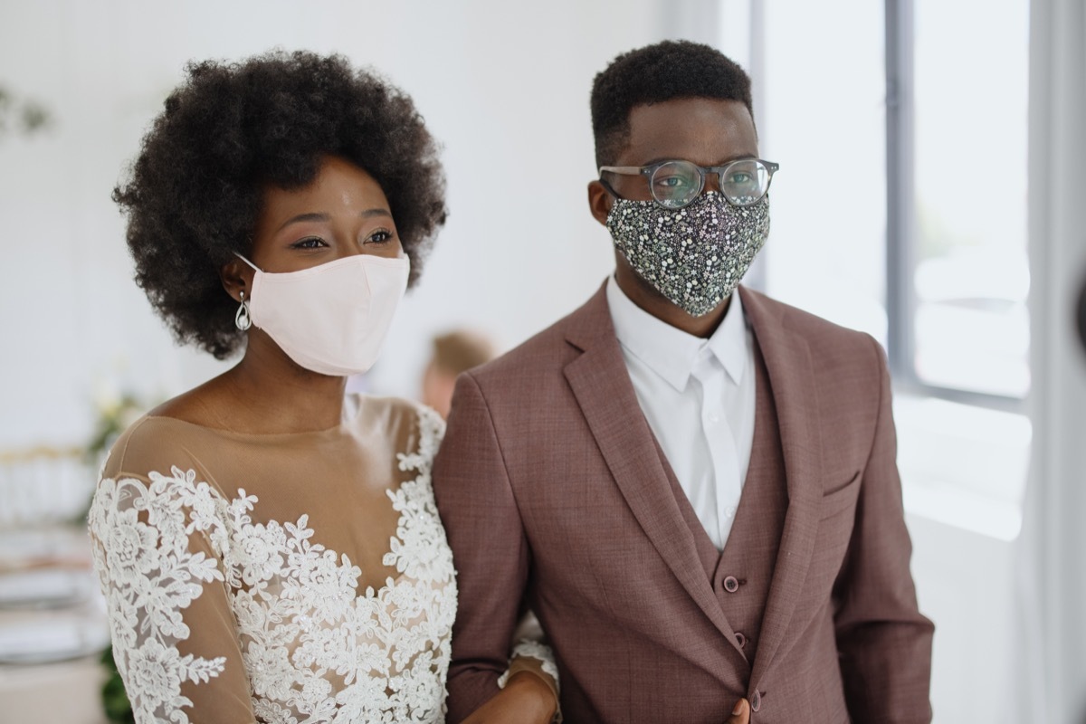 couple wears face protective masks at the reception of their wedding