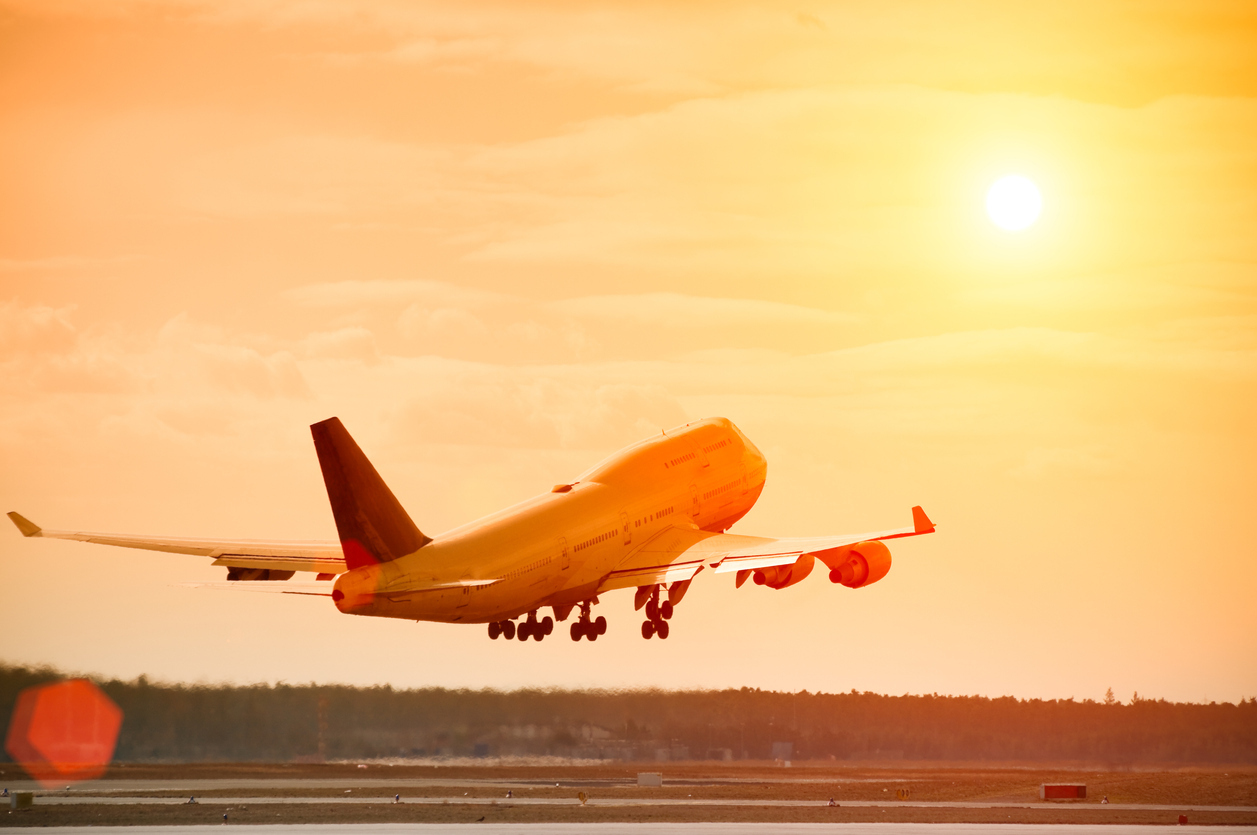 A commercial jetliner taking off at sunset on a hot day