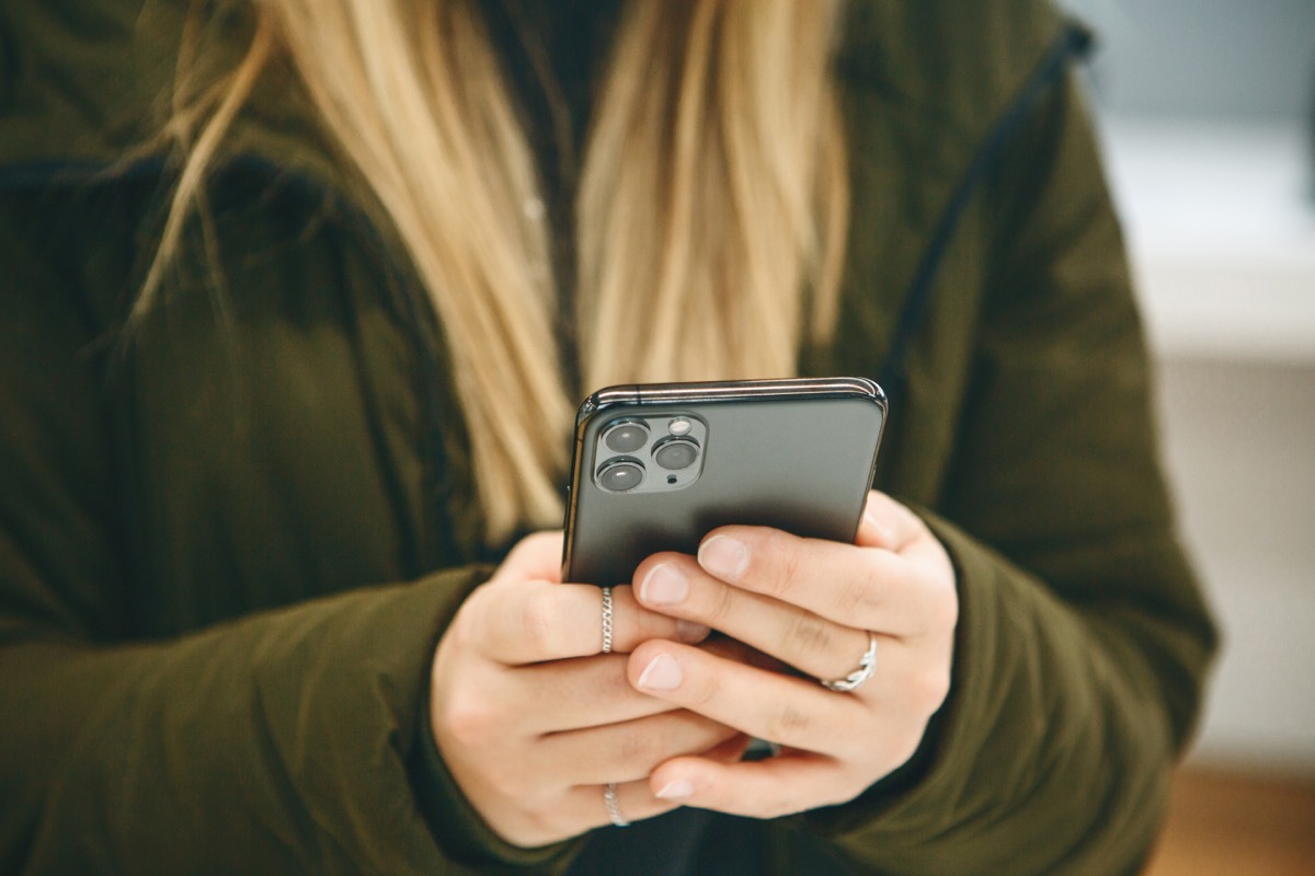 The girl uses a new cell phone with a triple camera.