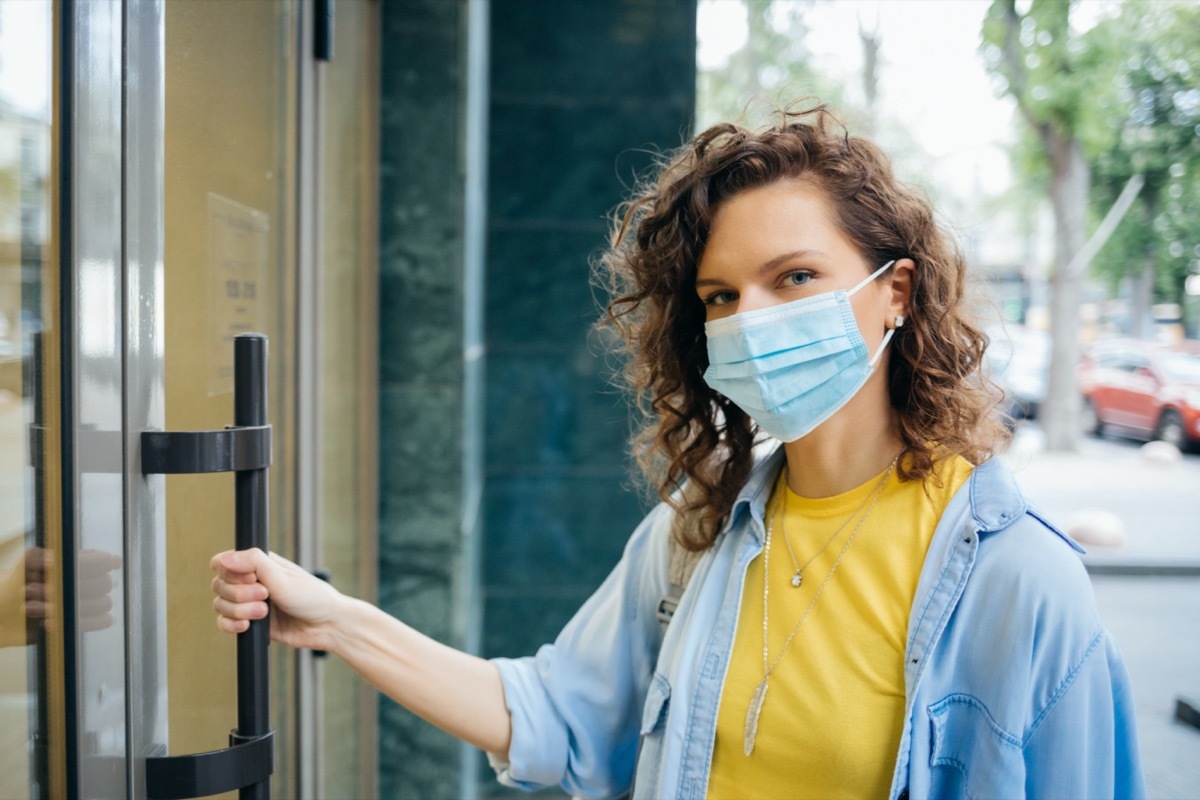 woman in protective mask opens the door