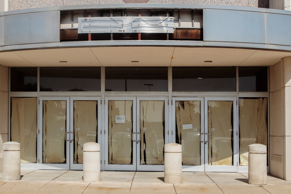 A shuttered storefront in a mall with paper over the windows