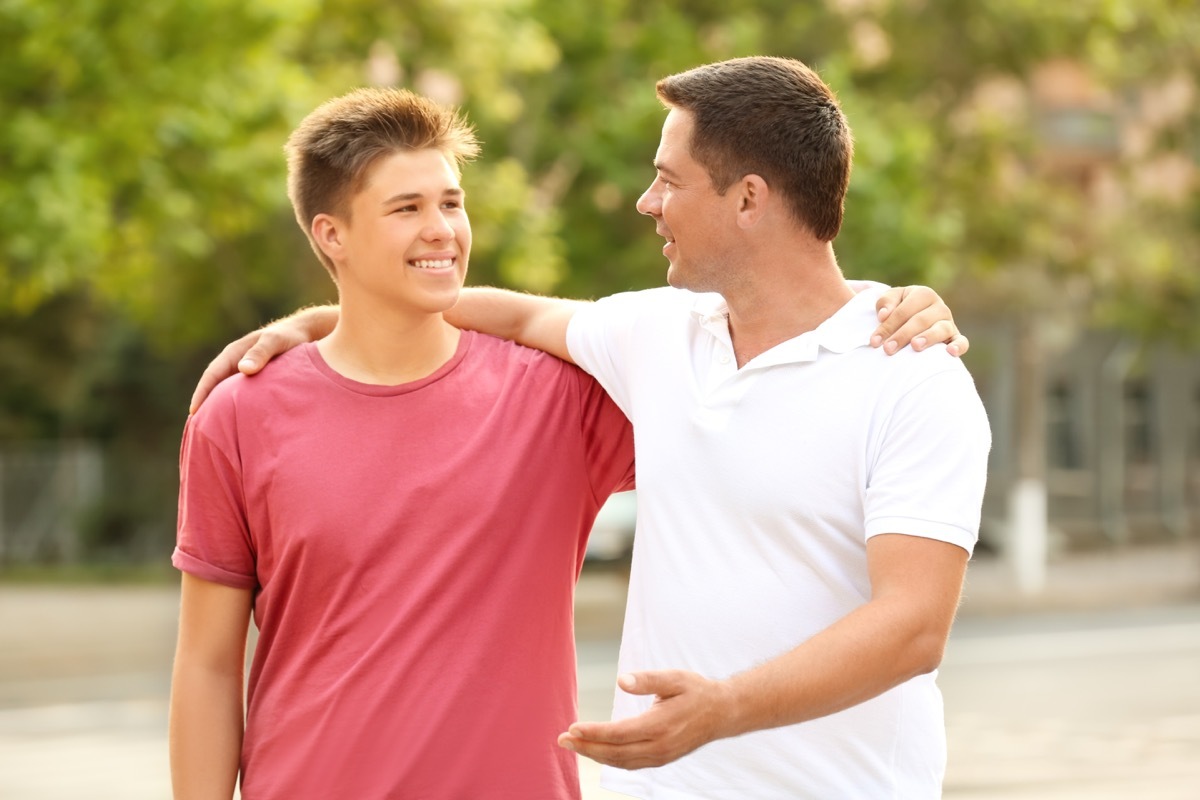 white father and son walking together in park