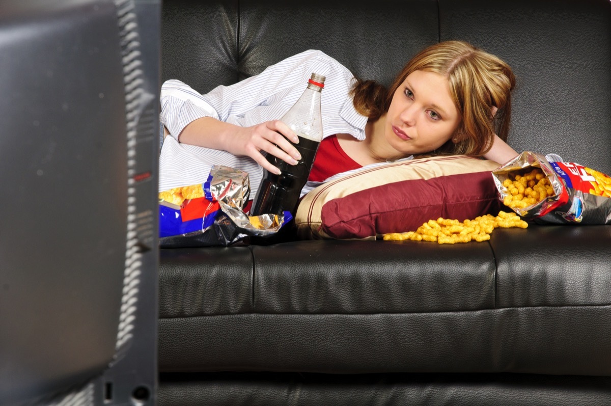 Girl snacking on couch while watching tv