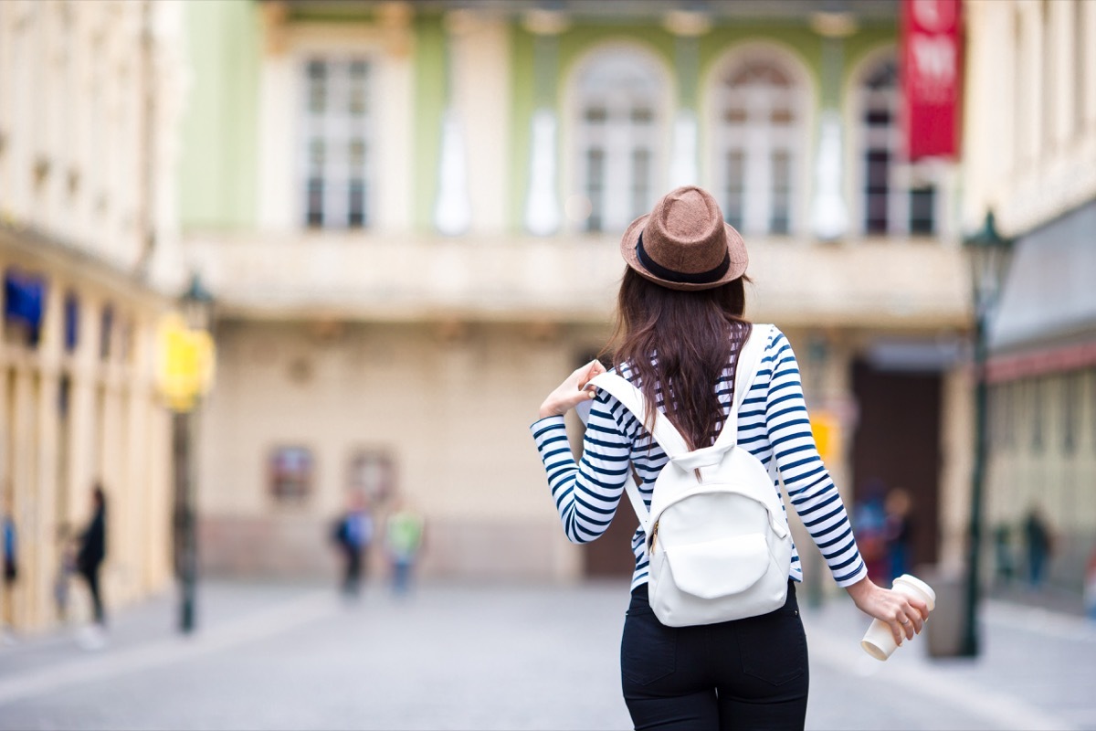 woman wearing a striped shirt and holding a white leather backpack