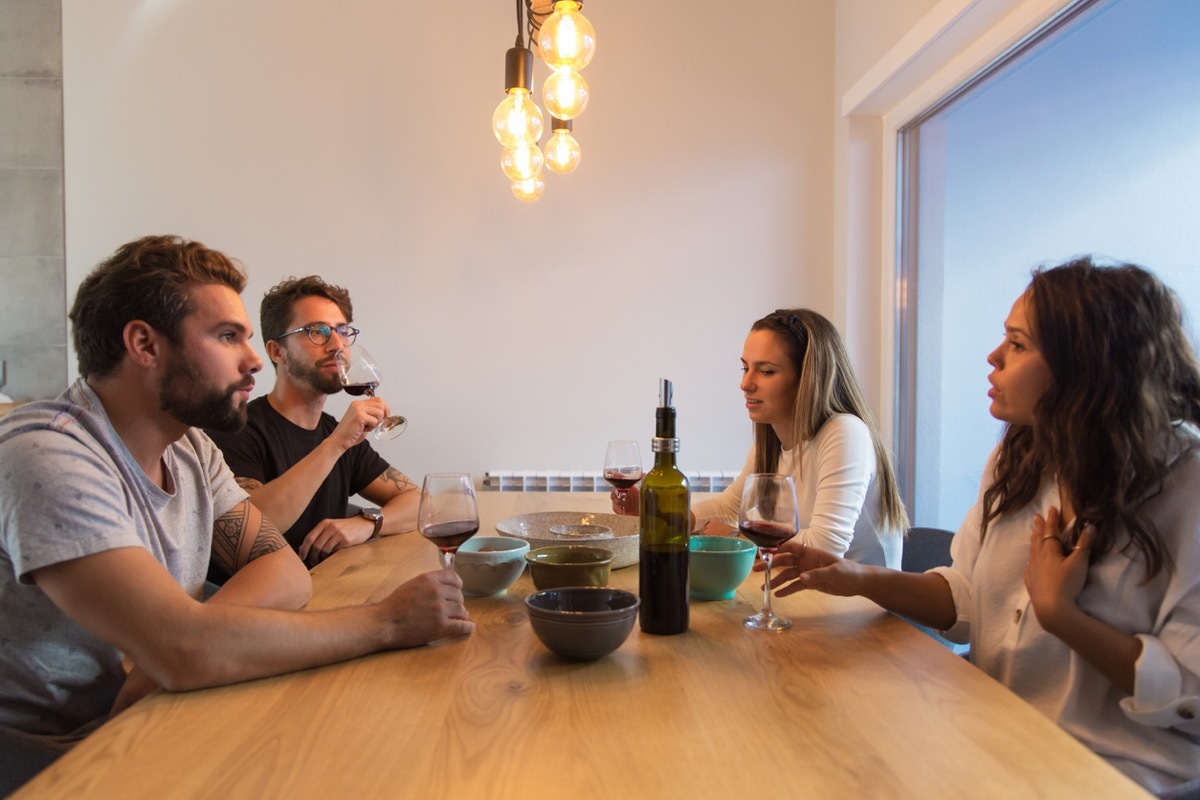 Beautiful brunette woman talking while drinking wine. Female friends sitting at table during dinner. Communication concept