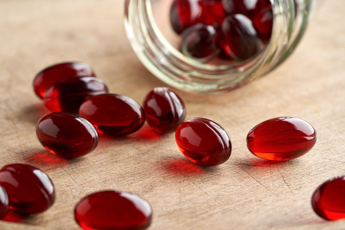 Krill oil pills spilled from a glass jar on a table