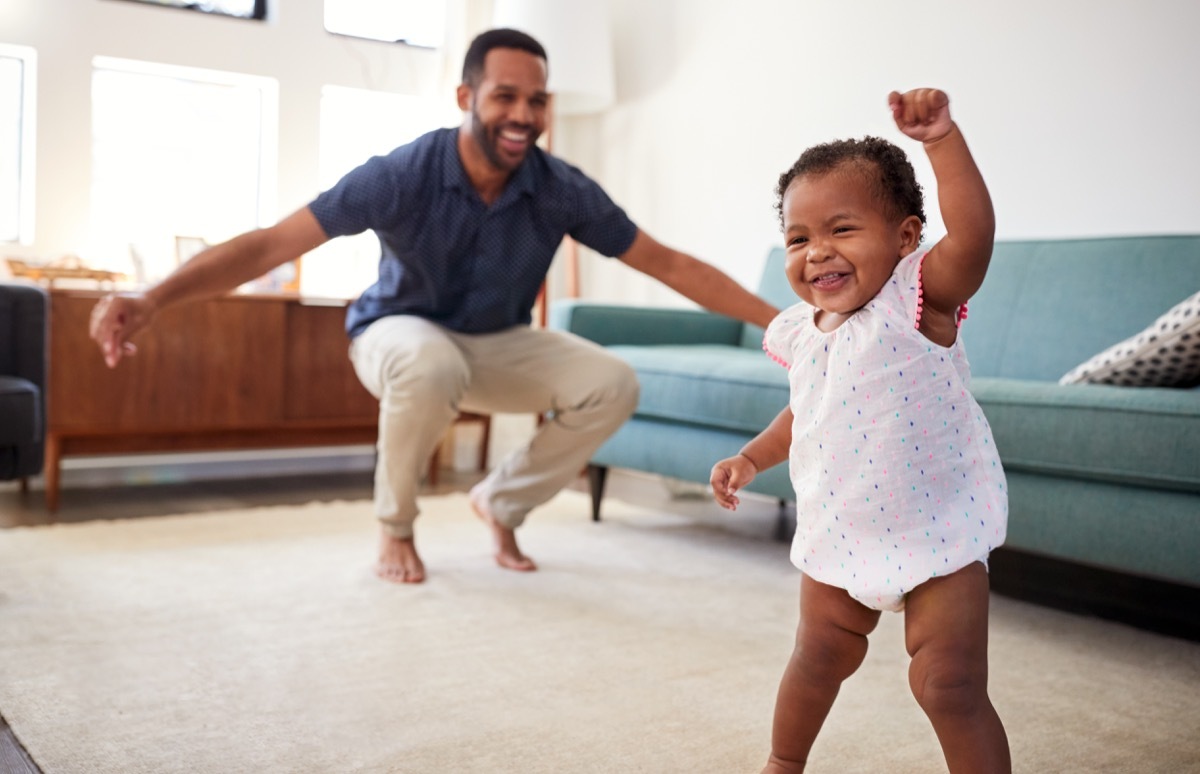 black baby girl walking and playing with dad