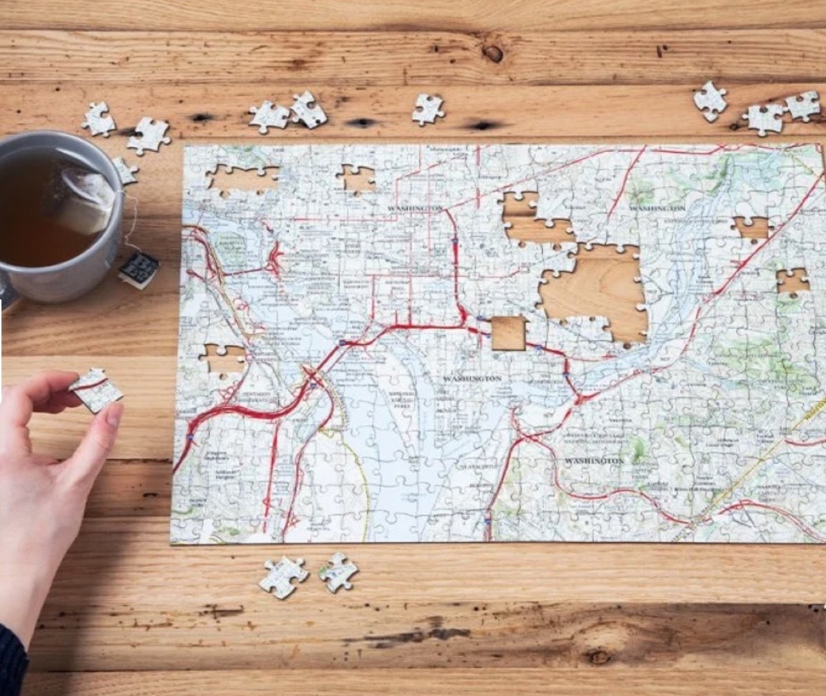 white hand putting together map jigsaw puzzle