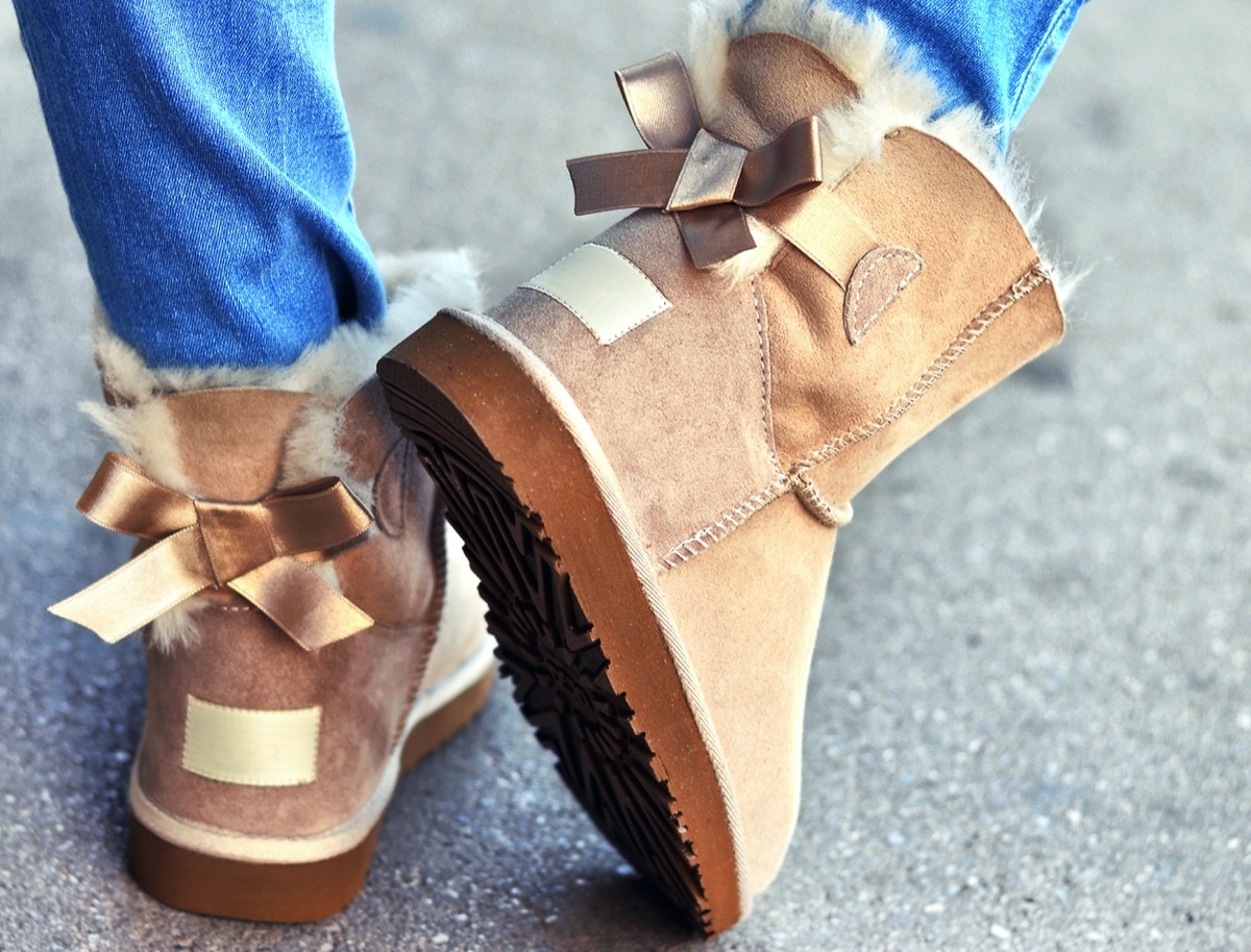 Woman in jeans wearing warm, fuzzy sheepskin boots ,walking on the street