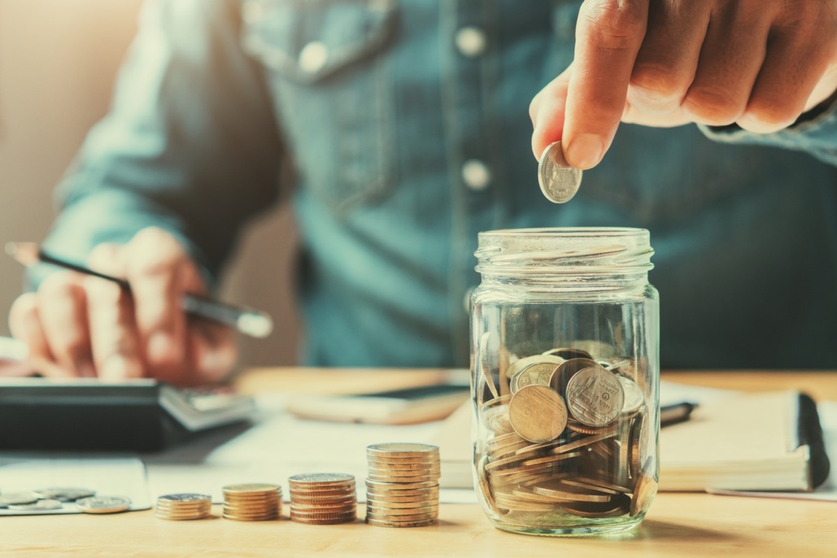 man putting coins in a jar