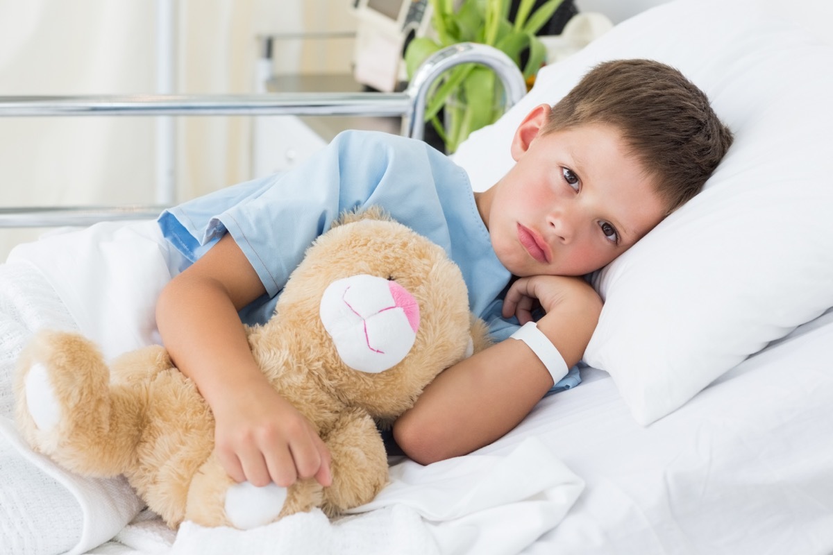 boy sick in hospital bed holding teddy bear