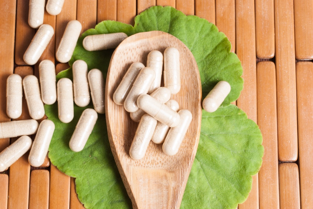 Ginko biloba capsules on a wooden spoon and ginko leaf