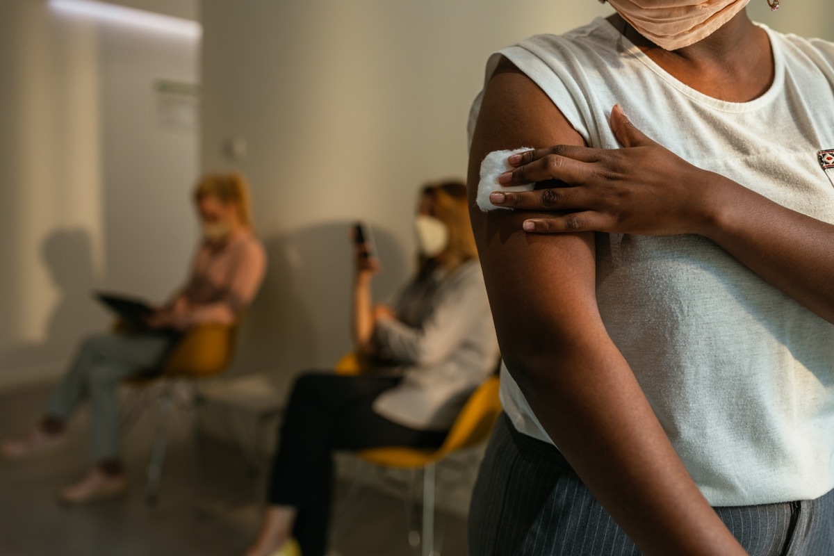 woman who has just been vaccinated holding bandage at the site of the sting in waiting room