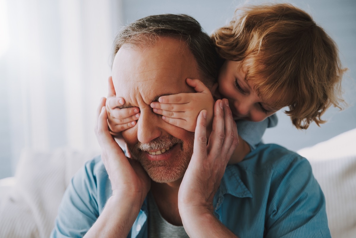 Grandkid covering grandpa's eyes being silly playing