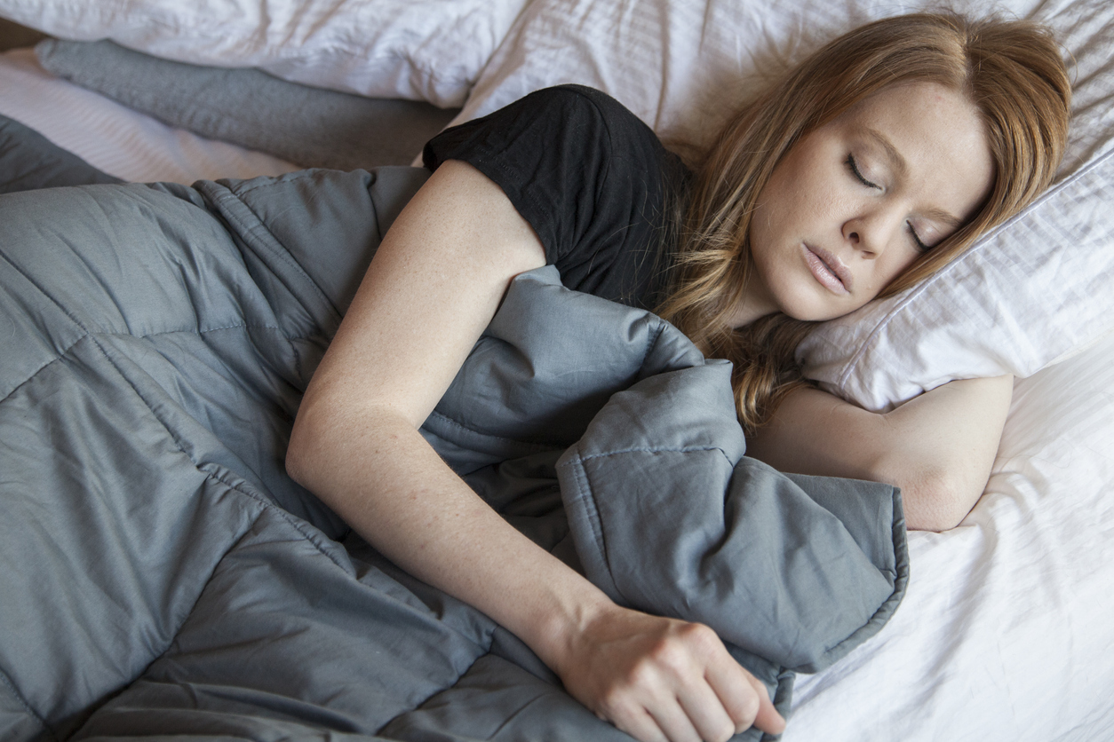 Woman sleeping under a weighted blanket.