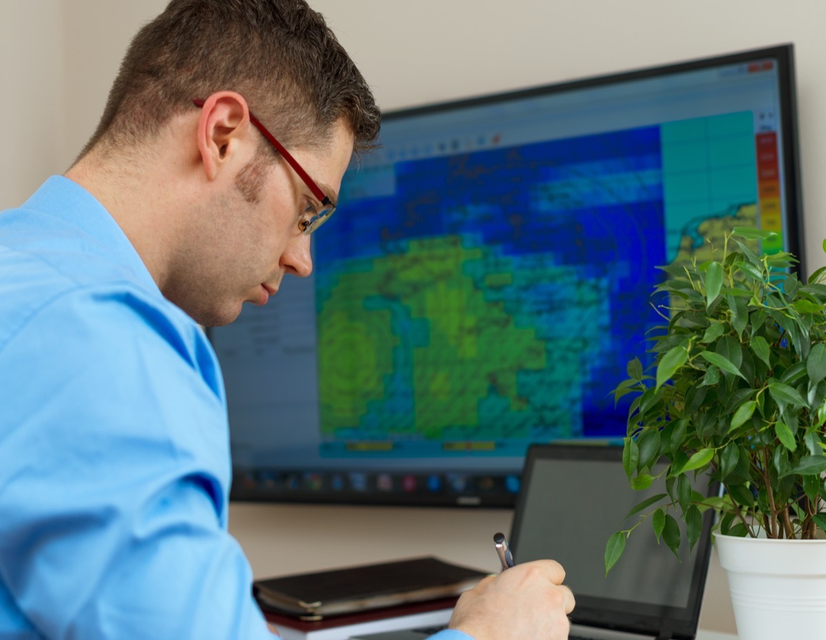 Handsome male meteorologist in glasses on his workplace.