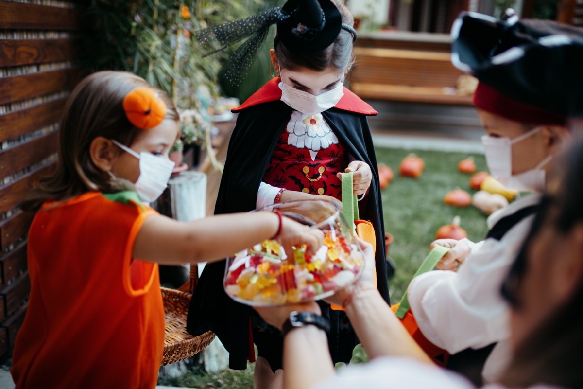 Group of kids trick or treating during Covid-19 pandemic wearing face masks