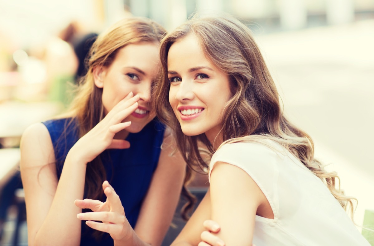 Two girls gossiping together